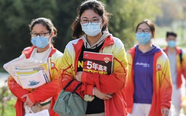 Des élèves de troisième année du secondaire portant des masques arrivent à l'école après que l'ouverture du trimestre a été retardée en raison de l'épidémie de coronavirus COVID-19, à Bozhou dans la province de l'Anhui, à l'est de la Chine, le 7 avril 2020 (Crédit : Photo STR / AFP)