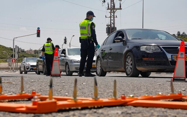 La police israélienne contrôle des voitures pour des violations du confinement à un barrage routier temporaire établi dans le village arabe israélien de Deir el-Assad pendant la crise du coronavirus, le 16 avril 2020. (Crédit : Ahmad GHARABLI / AFP)