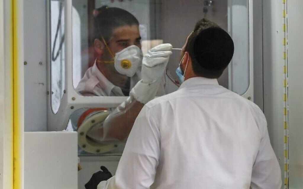 Un personnel soignant du Magen David Adom effectue un test de dépistage du coronavirus sur un homme ultra-orthodoxe dans un site de dépistage mobile, dans le quartier Geula de Jérusalem, le 20 avril 2020 (Crédit : Ahmad Gharabli/AFP)