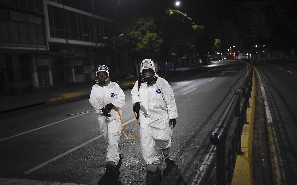 Des employés projettent du désinfectant dans les rues, une mesure préventive contre la propagation du noouveau coronavirus à Caracas, au Venezuela, le 21 mars 2020. (Crédit : AP Photo/Matias Delacroix)
