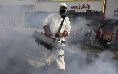 Un pompier désinfecte une place pour lutter contre le nouveau coronavirus, dans l'ouest de Téhéran, en Iran, le 13 mars 2020. (Vahid Salemi/AP)