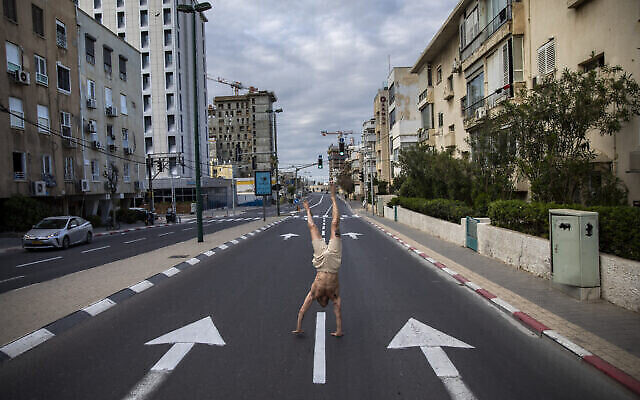 Un Israélien fait l'équilibre dans une rue vide de Tel Aviv pendant le confinement imposé par le coronavirus, le 8 avril 2020. (AP Photo/Oded Balilty)