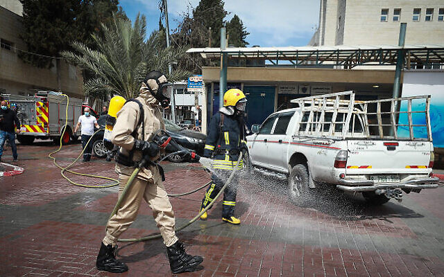 Des employés municipaux palestiniens désinfectent le parking d'un hôpital dans la ville de Ramallah en Cisjordanie, le 12 mars 2020. (Flash90)