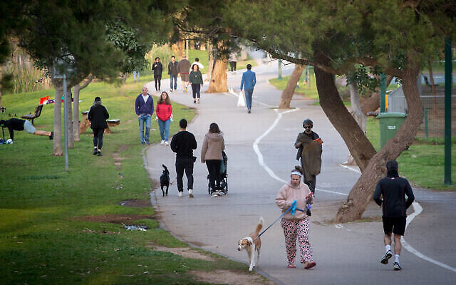 Des Israéliens promènent leur chien et font du sport au parc HaYarkon de Tel Aviv, le 22 mars 2020. (Crédit : Miriam Alster/Flash90)