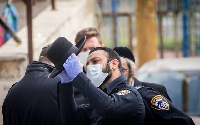 Des agents de police ferment des synagogues et infligent des amendes à des ultra-orthodoxes dans le quartier de Bukharim à Jérusalem, le 6 avril 2020 (Crédit : Yonatan Sindel/Flash90)