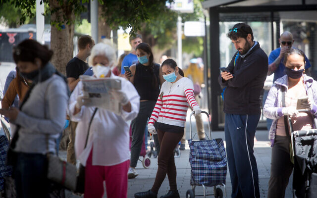 Des clients attendent devant un supermarché à Tel Aviv, le 7 avril 2020. (Crédit : Miriam Alster/Flash90)