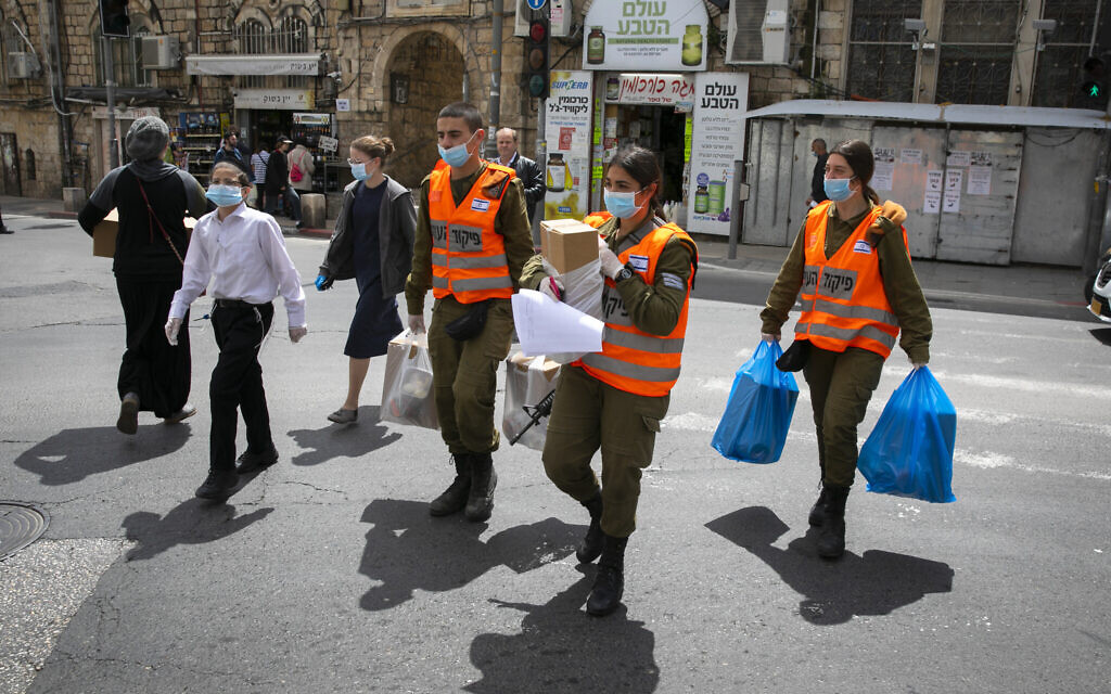 Des soldats du commandement intérieur distribuent des colis alimentaires aux personnes âgées obligées de rester confinées en raison de la crise du coronavirus avant la fête juive de Pessah, dans un quartier haredim de Jérusalem, le 7 avril 2020 (Crédit : Olivier Fitoussi/Flash90)