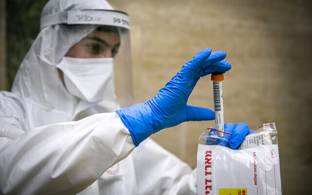 Un membre de l'équipe médicale du Magen David Adom, portant un équipement de protection, manipule un test de coronavirus effectué sur un patient à Jérusalem, le 17 avril 2020. (Olivier Fitoussi/Flash90)