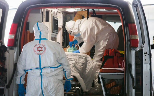 Des employés du Magen David Adom dans des vêtements de protection contre le coronavirus évacuent un malade aux abords d'une unité de prise en charge COVID-19 de l'hôpital Shaare Zedek de Jérusalem, le 20 avril 2020. (Crédit : Nati Shohat/Flash90)