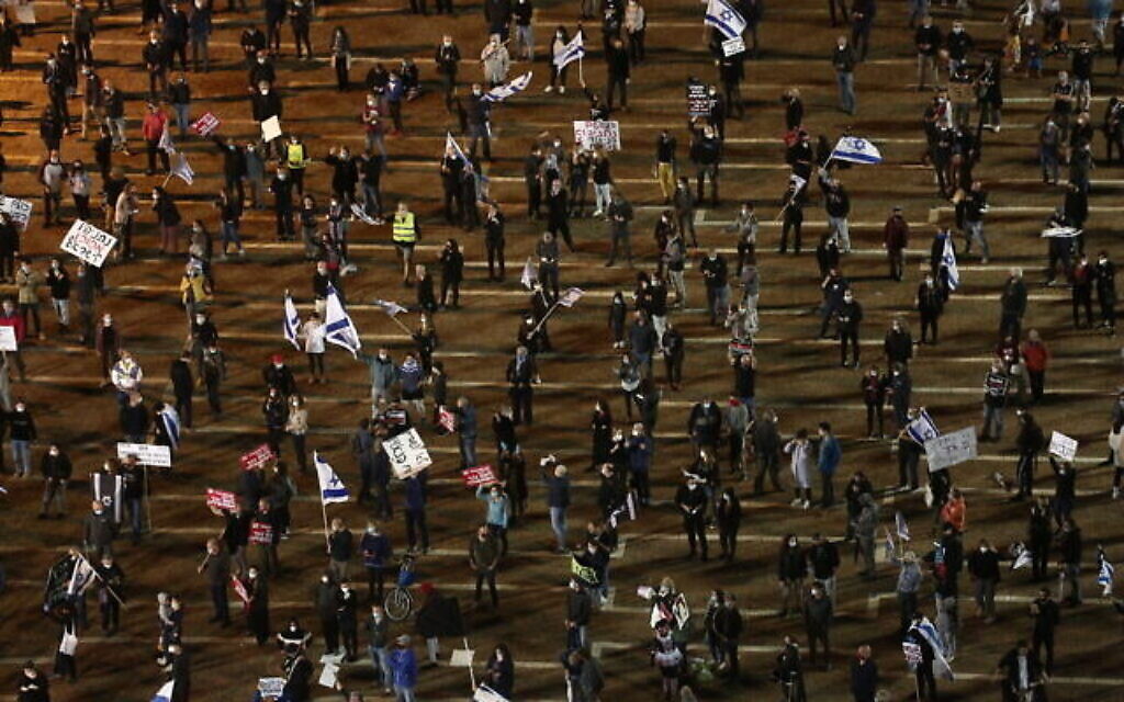 Gardant entre eux une distance de deux mètres, des milliers de manifestants assistent à une manifestation des "drapeaux noirs" à Tel Aviv, le 25 avril 2020 (Crédit : Miriam Alster/Flash90)