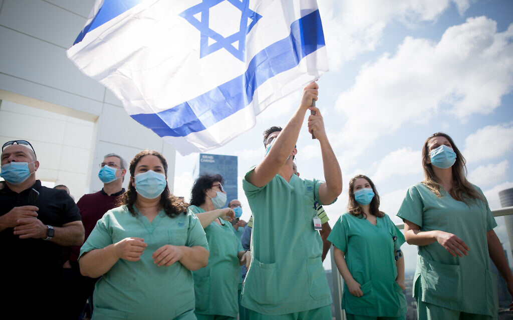 Le personnel médical acclame une équipe de voltige de l'armée de l'air israélienne survolant l'hôpital Ichilov à Tel Aviv, lors du 72e anniversaire de l'indépendance d'Israël, Yom HaAtsmaout, le 29 avril 2020. (Miriam Alster/Flash90)