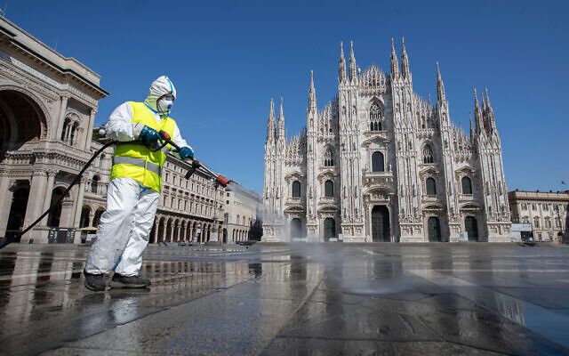 Un employé désinfecte la place Duomo dans le centre de Milan, en Italie, le 31 mars 2020 (Crédit : AP/Luca Bruno)
