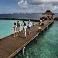 Des touristes étrangers arrivant dans une résidence de vacances sur l'île de Kurumba, aux Maldives, le 12 février 2012. (Gemunu Amarasinghe/AP)
