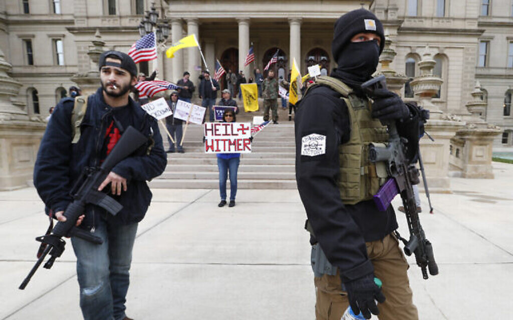 Des manifestants portent des armes devant les marches de bâtiment du Capitol de l'Etat du Michigan à Lansing, aux États-Unis, le 15 avril 2020. (Crédit : AP/Paul Sancya)