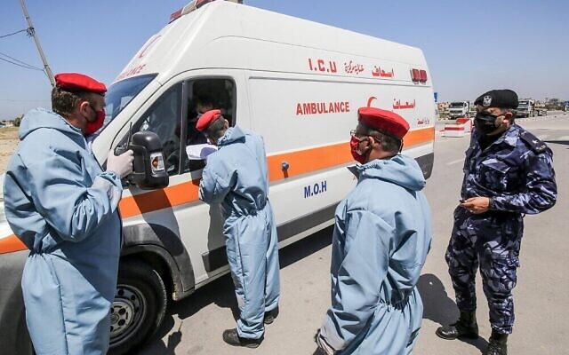 Les forces de sécurité du Hamas, le groupe terroriste qui dirige la bande de Gaza, vérifient les papiers d'un ambulancier au poste frontière de Rafah avec l'Égypte le 13 avril 2020. (Crédit : Said Khatib/AFP)
