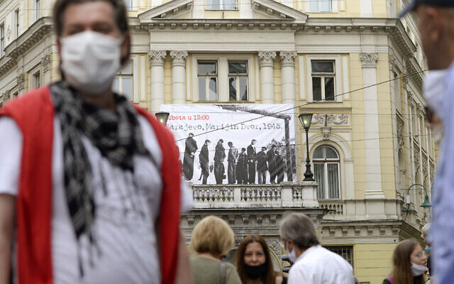 Des gens devant une bannière montrant des victimes exécutées par pendaison en 1945 par le régime croate pro-nazi oustachi pendant la Seconde Guerre mondiale, à Sarajevo, en Bosnie, le 16 mai 2020. (Crédit : AP / Kemal Softic)
