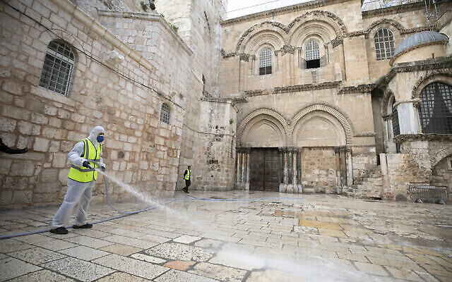 Les employés de la municipalité de Jérusalem désinfectent le parvis devant l'église fermée du Saint-Sépulcre comme mesure contre la propagation du coronavirus, le 30 mars 2020. (Crédit : Olivier Fitoussi / Flash90)