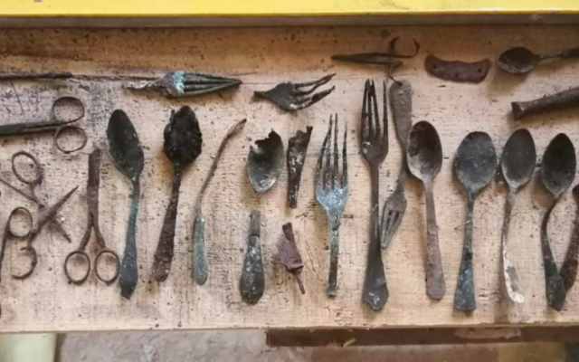 Des cuillères, couteaux, fourchettes et ciseaux cachés dans un conduit de cheminée du bloc 17 du camp de concentration d'Auschwitz en Pologne, retrouvés en avril 2020. (Crédit : Fonds national autrichien pour les victimes du nazisme/Kaczmarczyk/Marszałek)