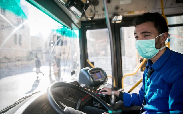 Un chauffeur de bus porte un masque facial par crainte du coronavirus dans le centre-ville de Jérusalem, le 16 mars 2020.(Crédit : Yonatan Sindel/Flash90)