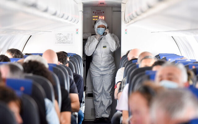 Photo d'illustration : Une employée portant une combinaison de protection à bord d'un avion, à l'aéroport Ben-Gurion de Tel Aviv, le 13 mai 2020 (Crédit : Yossi Zeliger/Flash90)