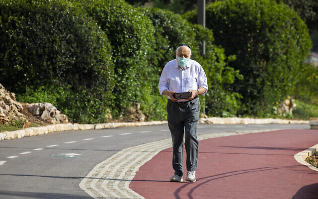 Un homme âgé, portant un masque en pleine crise de la COVID-19, se promène dans le parc Saker à Jérusalem, le 19 avril 2020. (Crédit : Olivier Fitoussi/Flash90)