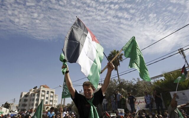 Le terroriste du Hamas Nael Barghouti brandit le drapeau vert islamique et le drapeau palestinien après son arrivée à Ramallah, en Cisjordanie, après sa libération dans le cadre d'un échange de prisonniers contre la libération de Gilad Shalit, soldat israélien détenu par le Hamas, le 18 octobre 2011 (Crédit :AP/Majdi Mohammed)