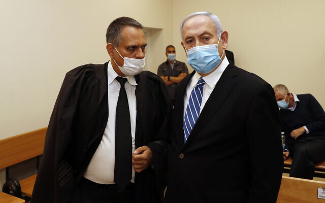Le Premier ministre Benjamin Netanyahu, (à droite), parle avec son avocat Micha Fettman, (à gauche), dans la salle du tribunal lors de l'ouverture de son procès pour corruption à la cour de district de Jérusalem, le 24 mai 2020. (Crédit : Ronen Zvulun/ Pool Photo via AP)