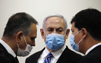 Le Premier ministre Benjamin Netanyahu (au centre) s'entretient avec les avocats Micha Fettman (à gauche) et Amit Hadad (à droite) dans la salle d'audience lors de l'ouverture de son procès pour corruption au tribunal de district de Jérusalem, le 24 mai 2020. (Ronen Zvulun/ Pool Photo via AP)