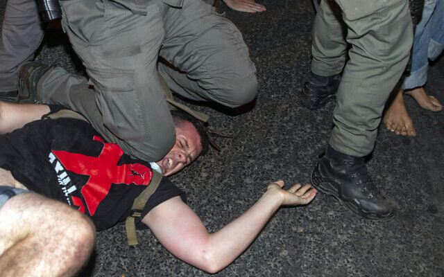 Un officier de police israélien met son genou sur le coup d'un manifestant pour procéder à son arrestation lors d'une manifestation contre le Premier ministre Benjamin Netanyahu, devant sa résidence à Jérusalem, le 22 juillet 2020. (AP Photo/Ariel Schalit)