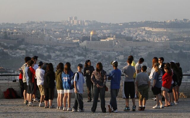 Un groupe touristique écoute un guide sur la promenade  Armon Hanatziv de Jérusalem avec la Vieille Ville en arrière-plan, en 2018. (Crédit : Miriam Alster/Flash90)