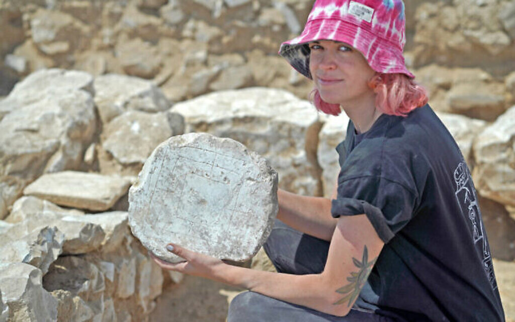 La lycéenne Jenny Vasiutin tient entre ses mains le jeu du "Moulin" trouvé pendant des fouilles menées par l'Autorité israélienne des antiquités à Rahat, ville bédouine du désert du Negev, (Crédit :Emil Aladjem/Israel Antiquities Authority)