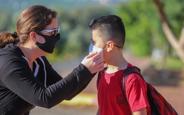 Un enfant israélien portant un masque sur le chemin de l'école au Moshav Yashresh, le 3 mai 2020. (Crédit : Yossi Aloni / Flash90)