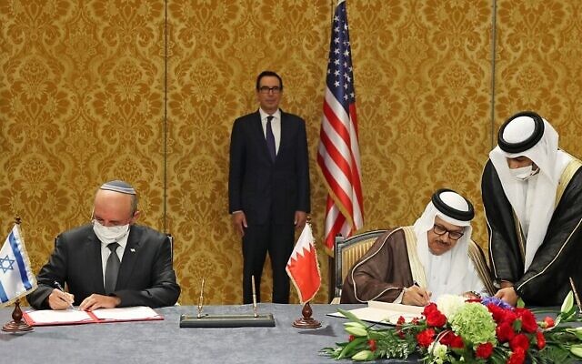 Le chef de la délégation israélienne, le conseiller à la sécurité Meir Ben-Shabbat, à gauche, et le ministre bahreïni des Affaires étrangères,  Abdullatif bin Rashid Al-Zayani, signent l'accord officialisant les relations diplomatiques entre les deux pays dans la capitale bahreïnie de Manama, avec le secrétaire d'Etat américain au Trésor, Steve Mnuchin, à l'arrière-plan, le 18 octobre 2020. (Crédit :  tRonen Zvulun/Pool/AFP)