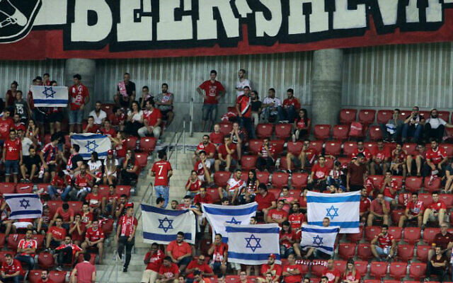 Les supporters de Hapoël Beer-Sheva agitent des drapeaux israéliens avant le match de football de barrage entre le Celtic et Hapoël Beer-Sheva au Turner Stadium dans la ville de Beer-Sheva, au sud d'Israël, le 23 août 2016. (Gil Cohen-Magen/AFP)