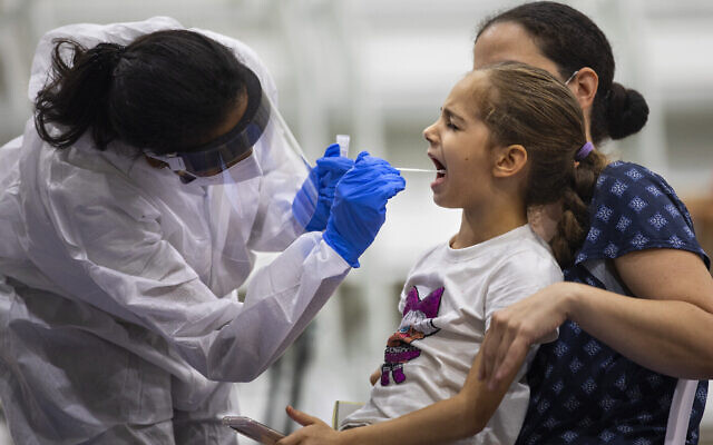 Une jeune fille est testée pour le coronavirus par un professionnel de la santé dans un centre de test COVID-19 installé sur un terrain de basket, à Ramat Gan, le 20 octobre 2020. (AP Photo/Oded Balilty)