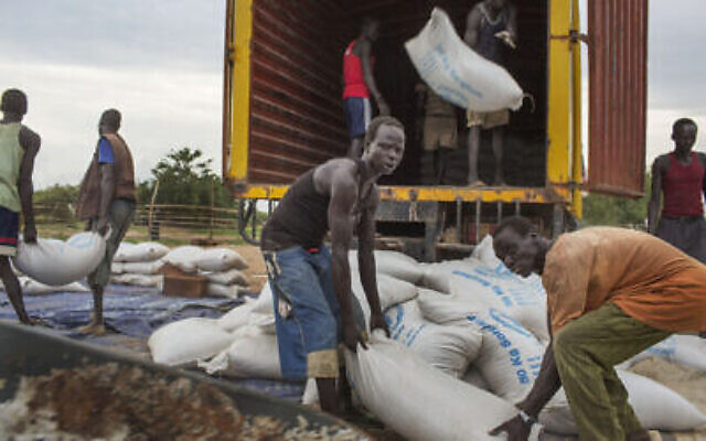 Des employés débarquent des sacs de céréales du programme alimentaire des Nations unies (WFP) à Minkaman, au sud Saoudan, le 26 juin 2014. (Crédit : AP Photo/Matthew Abbott)