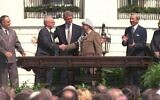 Bill Clinton regardant Yitzhak Rabin et Yasser Arafat se serrer la main, lors de la signature des accords d'Oslo, le 13 septembre 1993. (Crédit : GPO)
