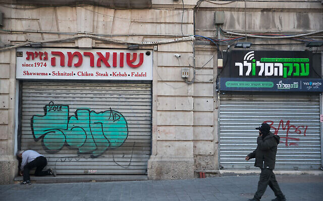 Un homme passe devant des magasins fermés dans la rue Jaffa, à Jérusalem, le 25 mars 2020. (Crédit : Yonatan Sindel/Flash90)