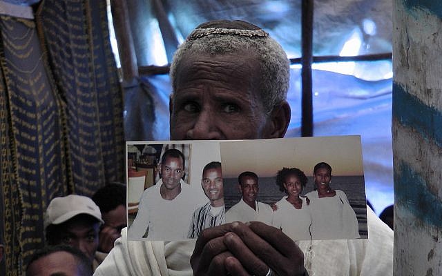 Un fidèle éthiopien à la synagogue d'Addis-Abeba priant et tenant des photos de membres de sa famille vivant en Israël. (Bernard Dichek/ Times of Israel)