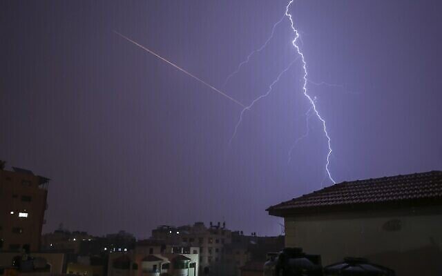 Cette photo prise depuis la bande de Gaza montre un tir de roquette côtoyer un éclair lors d'un orage le 15 novembre 2020. (Crédit : MOHAMMED ABED / AFP)