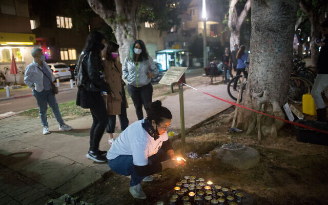 Une femme allume des bougies à la mémoire des femmes assassinées lors de violences domestiques, sur un mémorial situé sur le boulevard Rothschild, à Tel Aviv, à l'occasion de la Journée internationale de la violence contre les femmes, le 24 novembre 2020. (Miriam Alster/FLASH90)