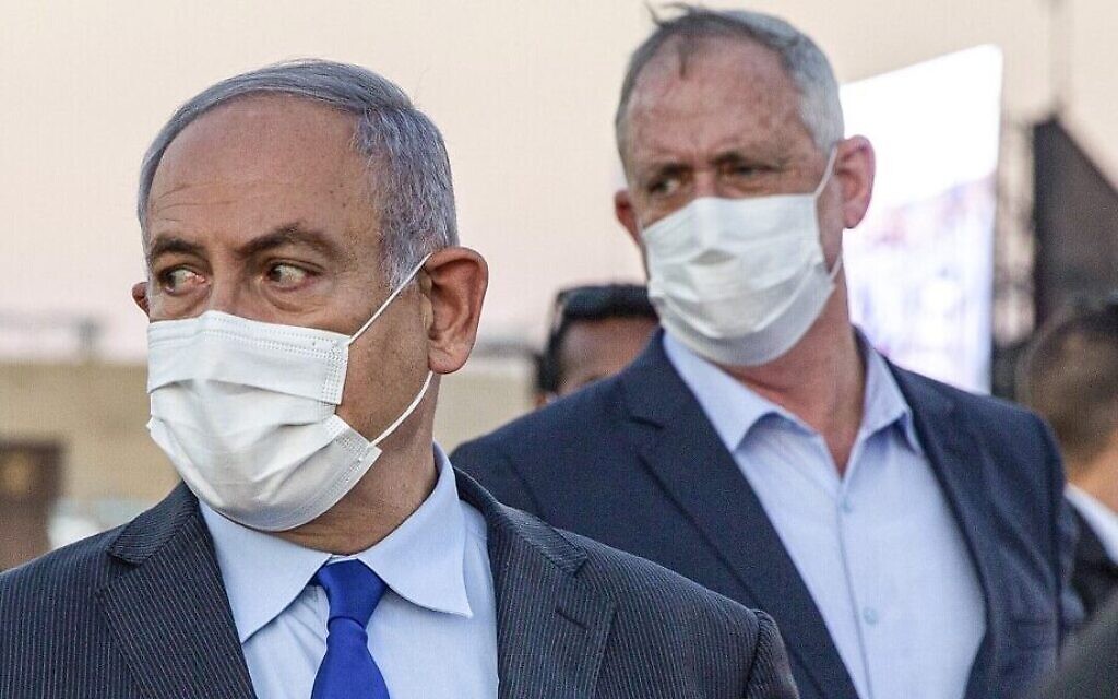 Le Premier ministre Benjamin Netanyahu (à gauche) et son partenaire de coalition, le ministre de la Défense Benny Gantz, tous deux masqués en raison de la pandémie de coronavirus COVID-19, arrivent pour assister à une cérémonie de remise de diplômes aux nouveaux pilotes sur la base aérienne d'Hatzerim près de Beer Sheva, le 25 juin 2020. (Ariel Schalit / POOL / AFP)