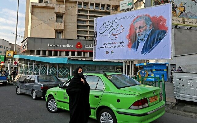 Une femme passe devant un panneau en hommage au scientifique nucléaire Mohsen Fakhrizadeh dans la capitale iranienne de Téhéran, le 30 novembre 2020. (Crédit : Atta Kenare/AFP)
