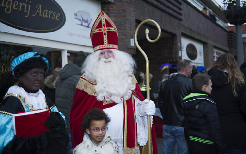 Un homme habillé en Saint Nicolas et une femme déguisée en Zwart Piet amusent les enfants sous la protection de la police dans le nord d'Amsterdam, aux Pays-Bas, le 16 novembre 2019. (Crédit : Cnaan Liphshiz/JTA)