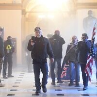 Les partisans du président américain Donald Trump prennent d'assaut le Capitole américain, enfumé par gaz lacrymogènes, le 6 janvier 2021 à Washington, DC. (Crédit : Saul LOEB / AFP)