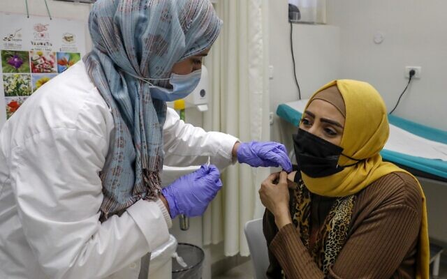 Une résidente palestinienne du quartier de Beit Hanina à Jérusalem-Est se fait vacciner contre le coronavirus dans un centre de santé de Clalit, le 12 janvier 2021. (Ahmad Gharabli/AFP)