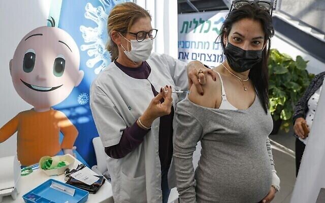 Une soignante israélienne administre une dose du vaccin de Pfizer-BioNtech à une femme enceinte dans un centre de la Clalit, à Tel Aviv, le 23 janvier 2021. (Crédit : AFP)