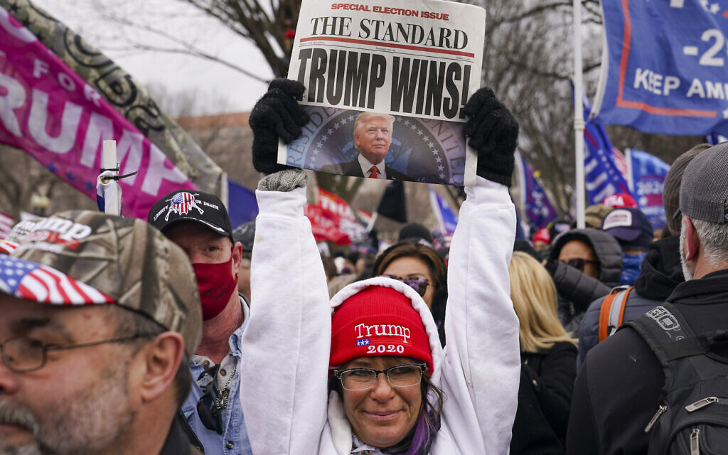 Une sympathisante du président Donald Trump brandit un journal avec une fausse manchette, le mercredi 6 janvier 2021 à Washington, peu avant l'assaut contre le Capitole américain. (AP Photo/John Minchillo)