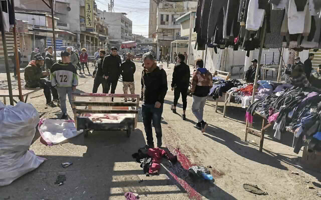 Des civils et des forces de sécurité sur le site d'un attentat à la bombe dans la zone commerciale animée de Bagdad, en Irak, le 21 janvier 2021. (AP Photo / Hadi Mizban)