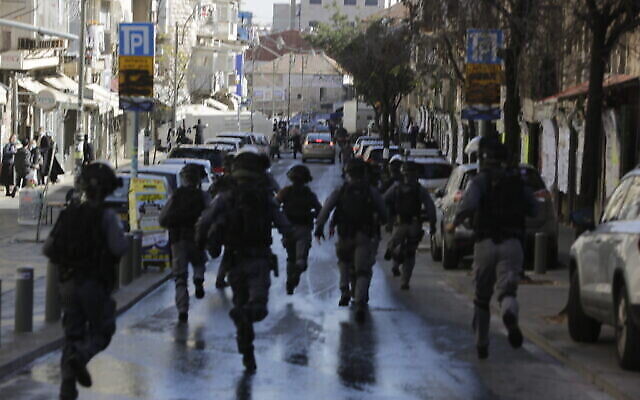 La police israélienne court dans un quartier ultra-orthodoxe de Jérusalem, le 24 janvier 2021. (Crédit : AP Photo/Sebastian Scheiner)